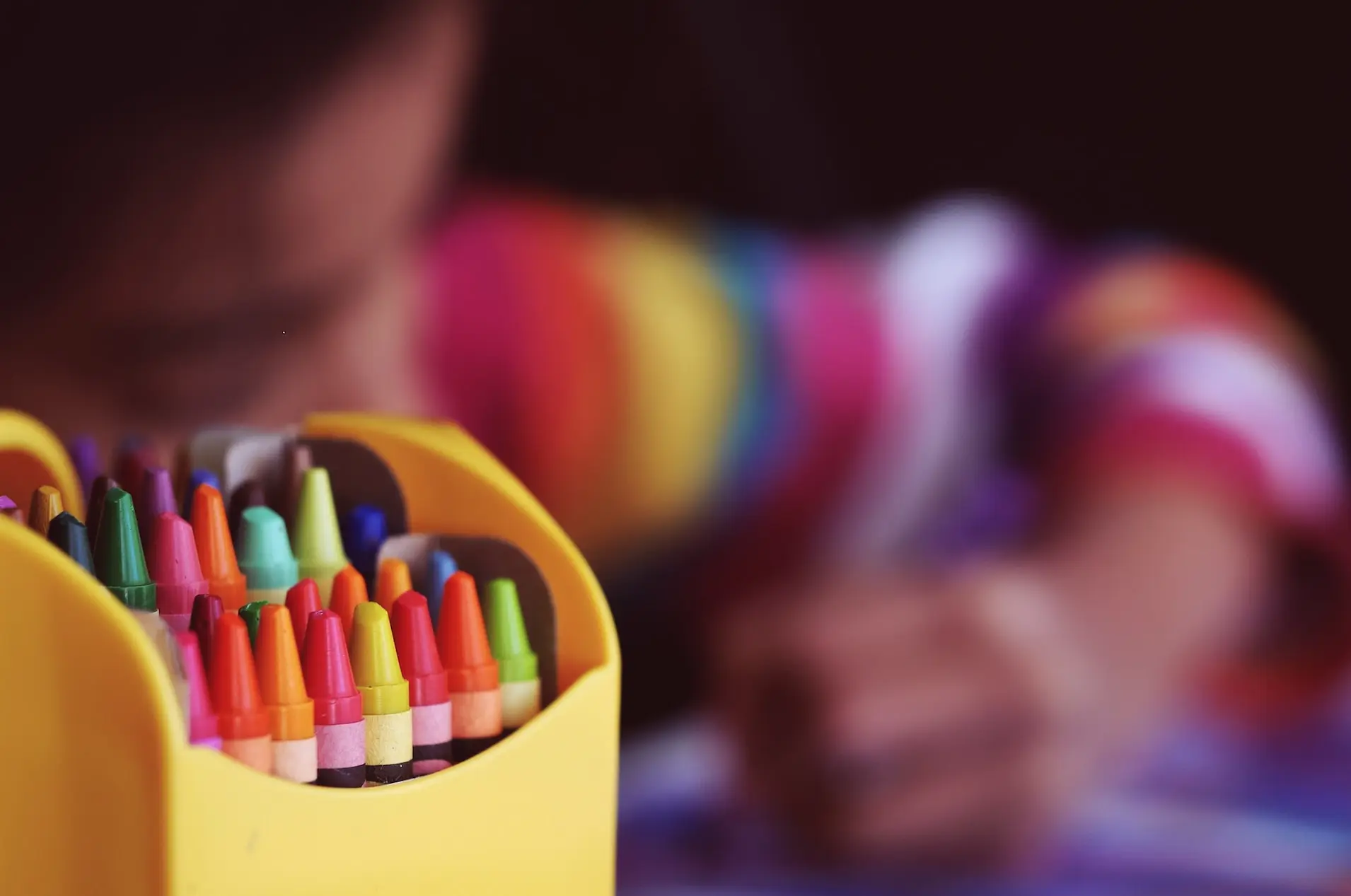 selective focal photo of crayons in yellow box